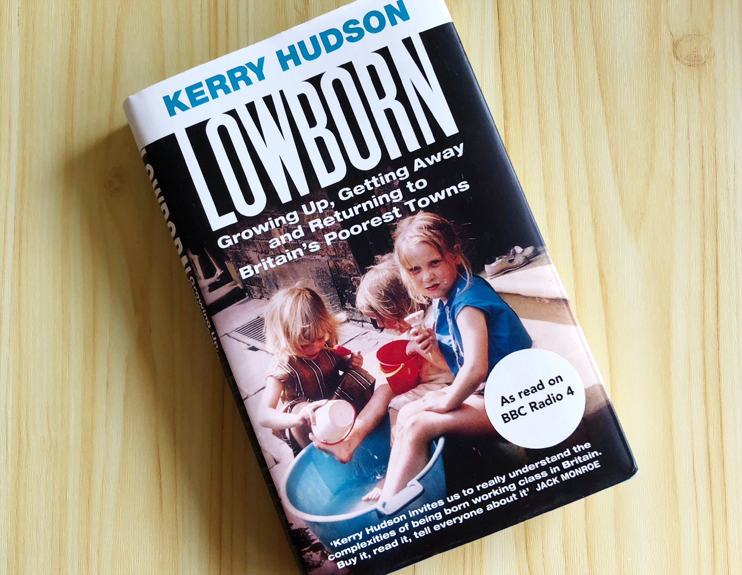 Foto do livro Lowborn: Growing Up, Getting Away and Returning to Britain's Poorest Towns de Kerry Hudson sobre uma mesa de pinus.