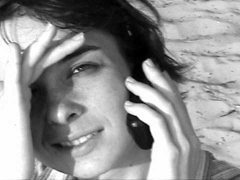 A imagem apresenta a personagem feminina do filme de Kléber Mendonça Filho, olhando para a câmera durante uma chamada telefônica. A imagem está em preto e branco.