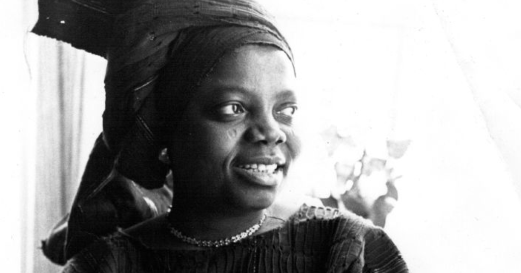 A imagem em preto e branco apresenta Buchi Emecheta, que é a autora de maio do Literatura Inglesa Brasil.