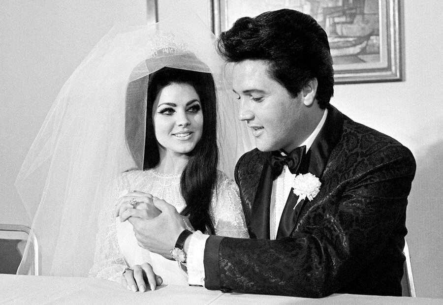 A foto, em preto e branco, contém o cantor Elvis Presley e sua esposa Priscilla Presley no dia de seu casamento.