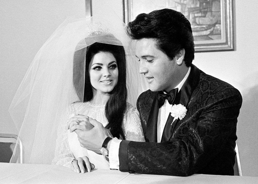 A foto, em preto e branco, contém o cantor Elvis Presley e sua esposa Priscilla Presley no dia de seu casamento.